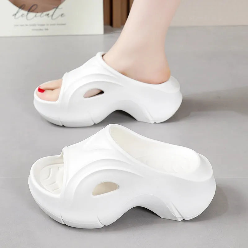 Women's white thick-sole EVA beach slippers with a round toe, shown on a sandy background.