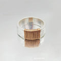 Geometric copper ring bracelet with a wide face and irregular coil design in a silver gold colour.