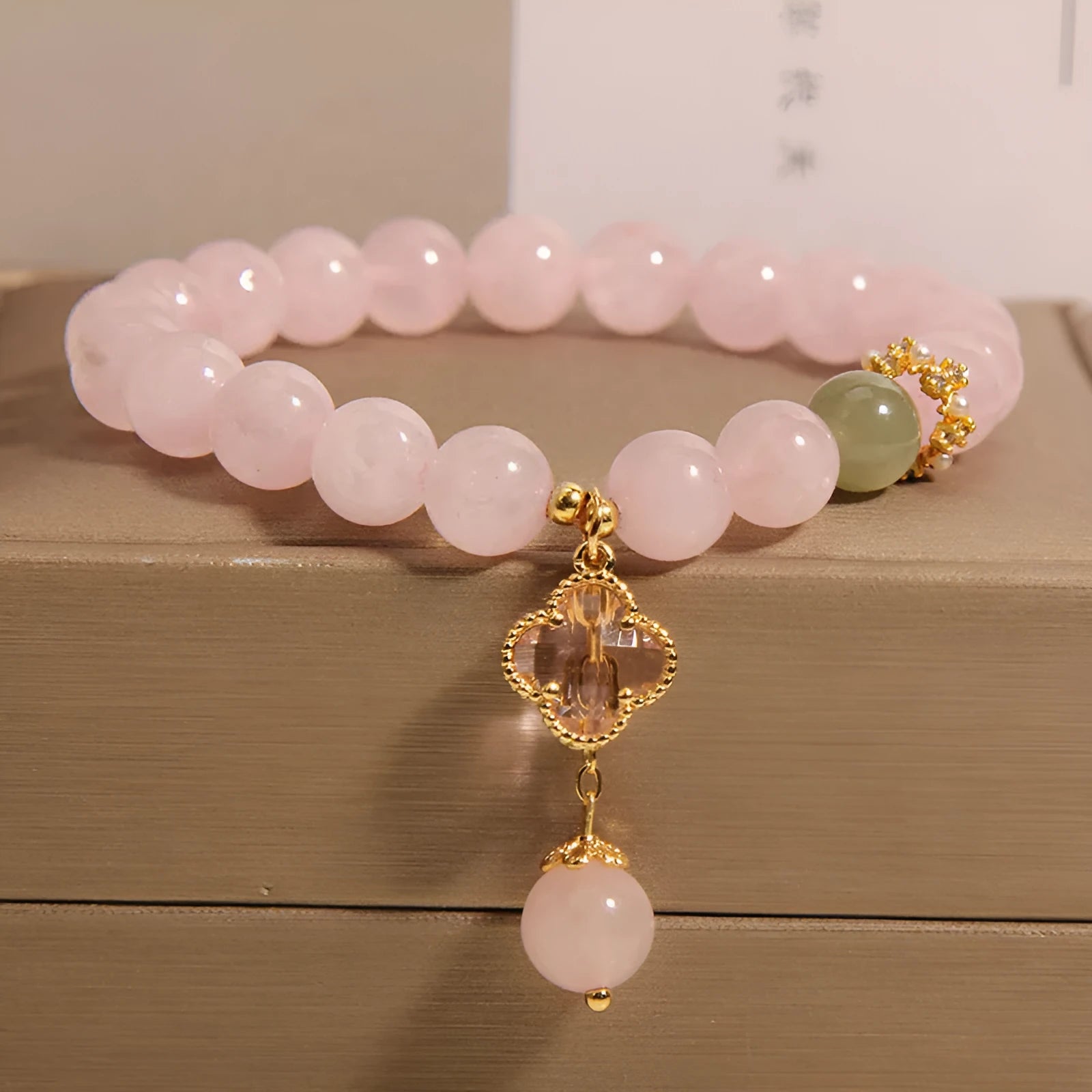 Pink crystal bracelet with four-leaf clover pendant and rhinestone details on women's wrist