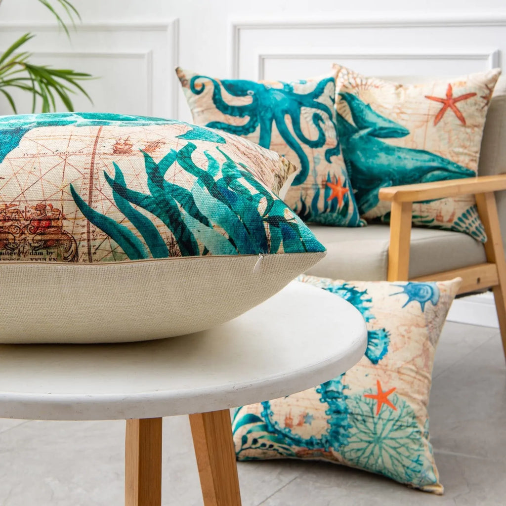 Square linen cushion cover with a detailed blue and green sea turtle print, shown on a grey sofa.