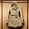 Women's khaki trench coat with double-breasted front and flight sleeves on hanger