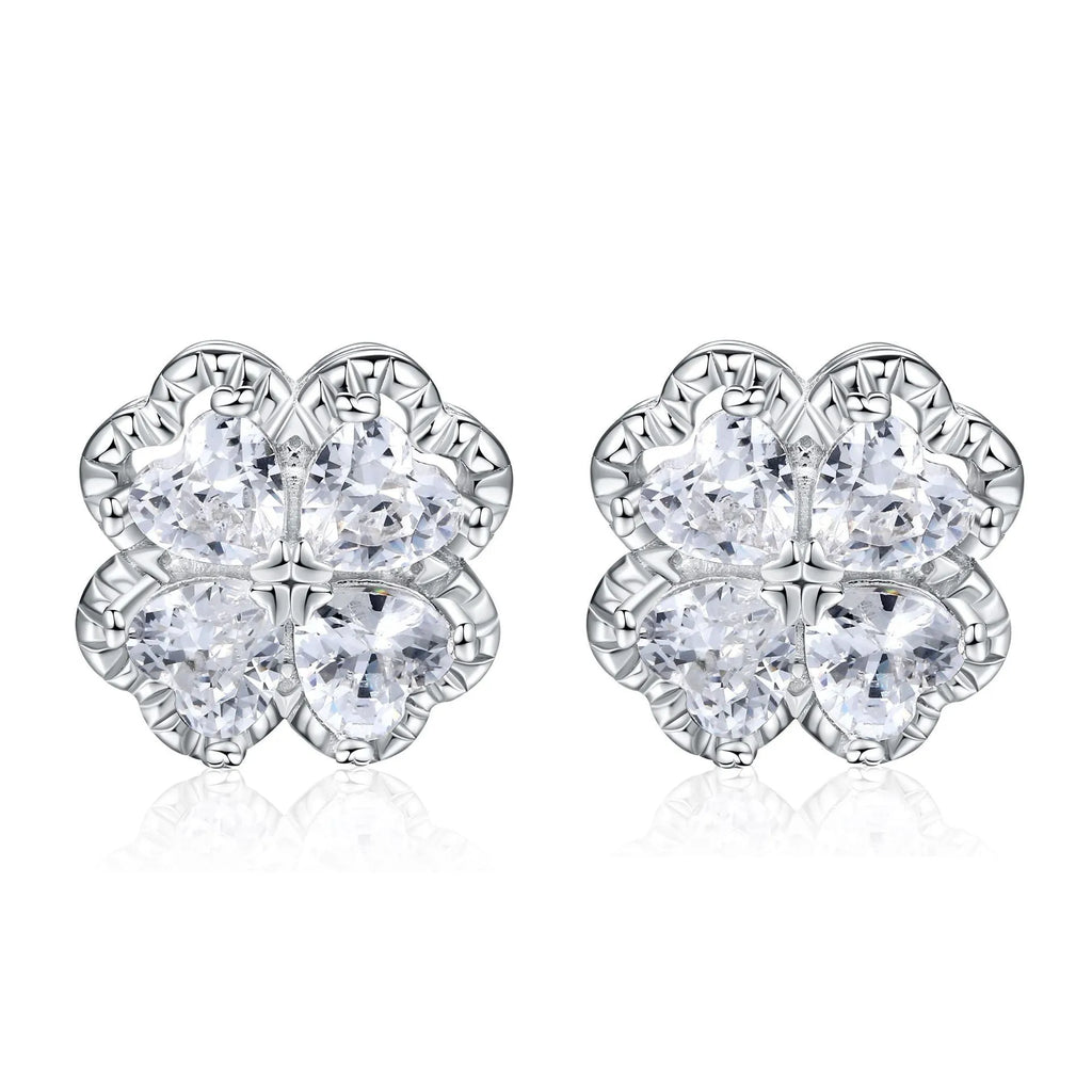 Close-up of a pair of heart-shaped 925 silver earrings with a four-leaf clover charm and zircon stones, in white gold colour.