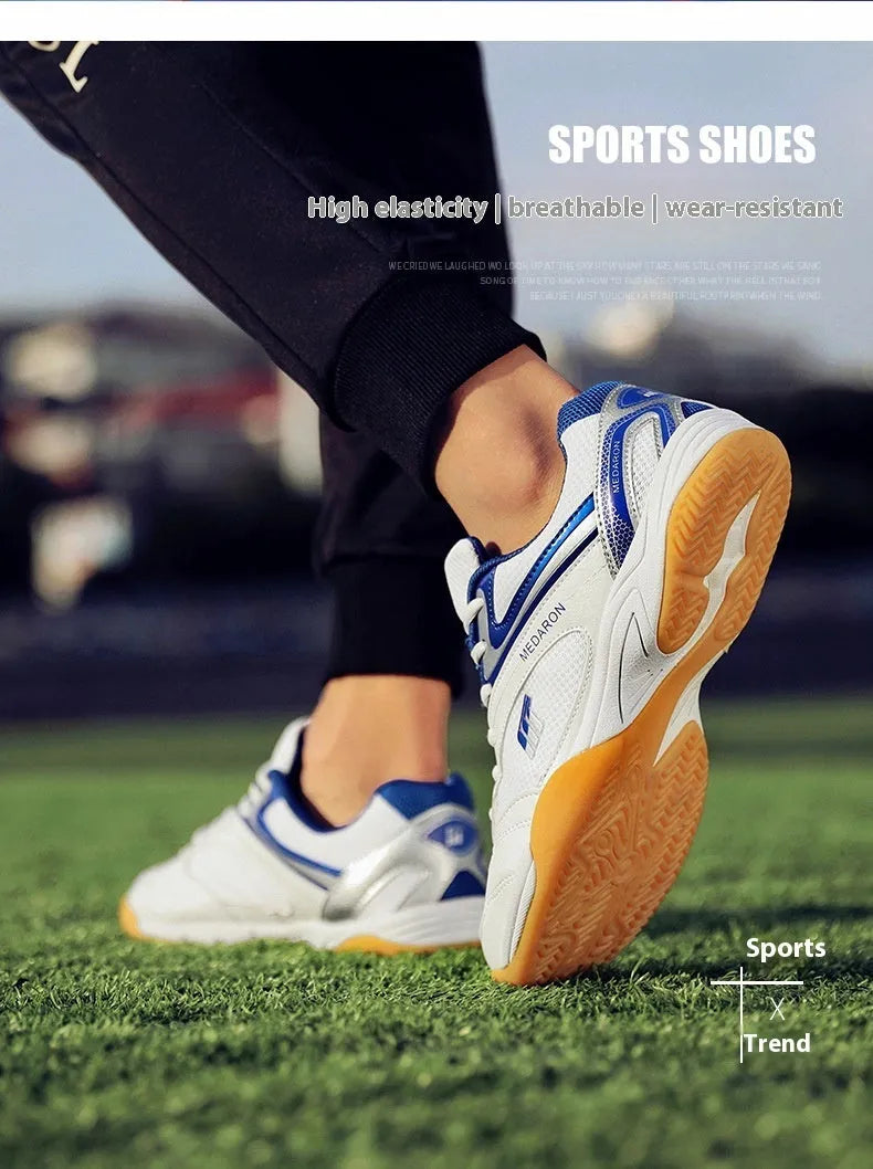 White and blue table tennis shoes with mesh panels and rubber sole on a court surface.