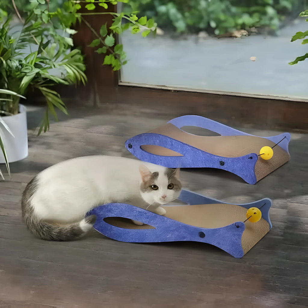 Blue fish-shaped cardboard cat scratcher with a wavy lounge surface and a red bell toy on a string.