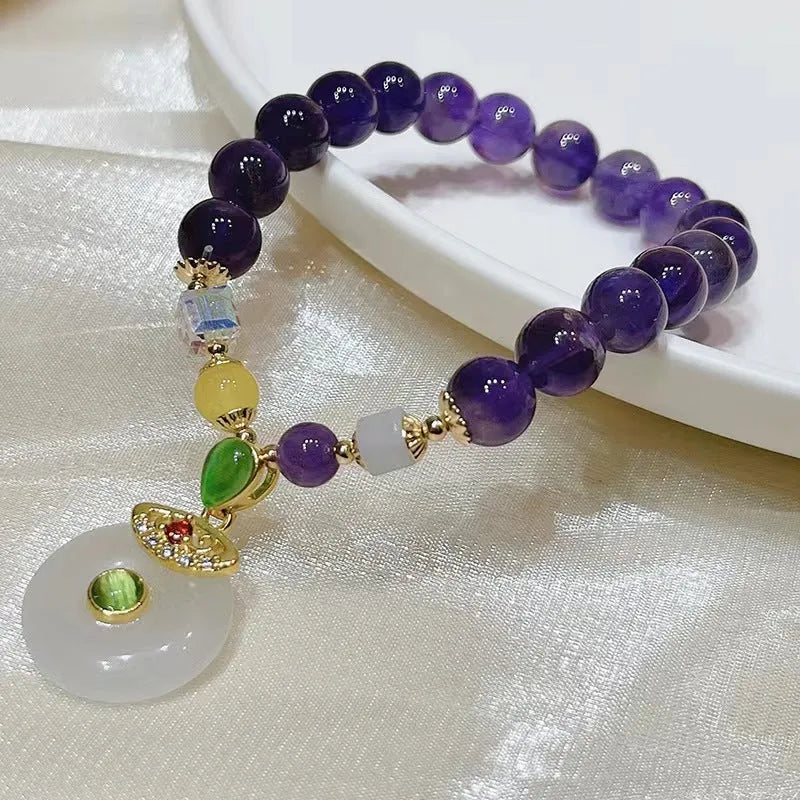 Purple crystal bracelet with ethnic money bag pendant and peace buckle closure on wrist