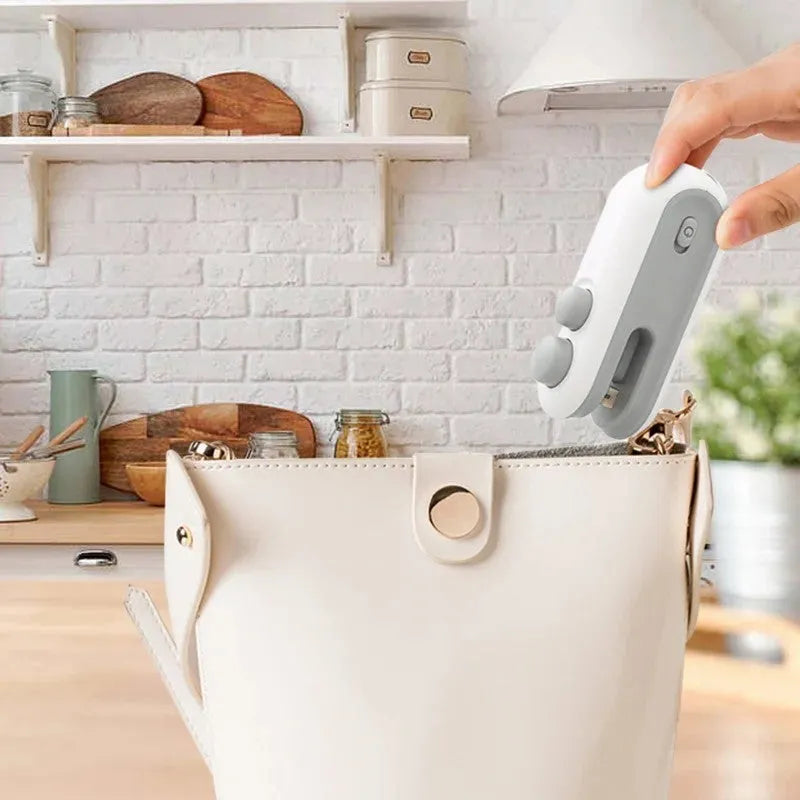 White handheld vacuum sealing machine with USB charging port and magnetic back for chip bags