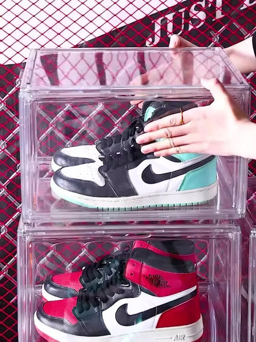 Clear acrylic shoe storage box with magnetic side door open, showing shoes inside.