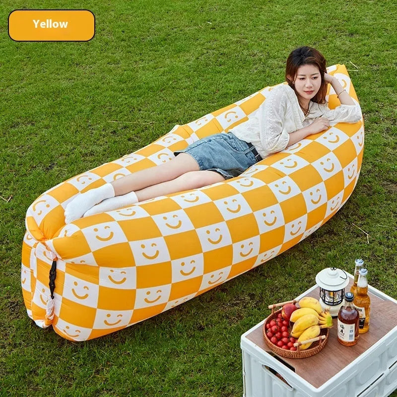 Inflatable portable sofa in a colourful design, shown folded to its 36cm by 27cm size and in use outdoors.
