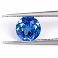 A selection of loose royal blue cultivated gemstones in heart, round, and pear shapes on a jeweller's cloth.