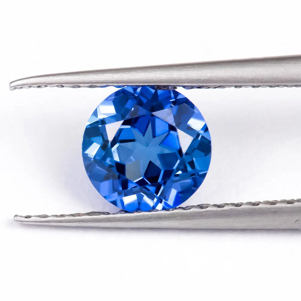 A selection of loose royal blue cultivated gemstones in heart, round, and pear shapes on a jeweller's cloth.
