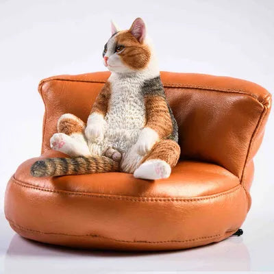Resin lazy cat car ornament with fabric sofa, approximately 7.5cm high.