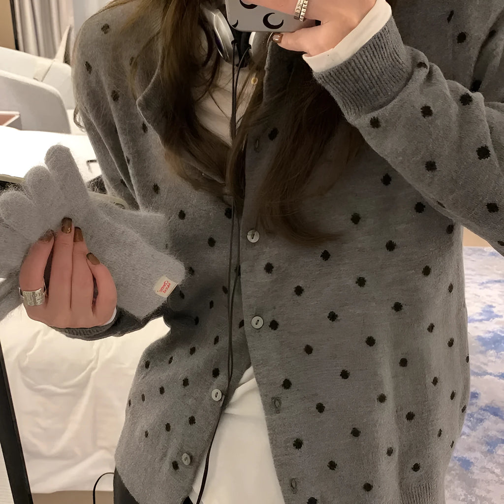 Grey dot patterned women's knitted cardigan with crochet flower details on a hanger.