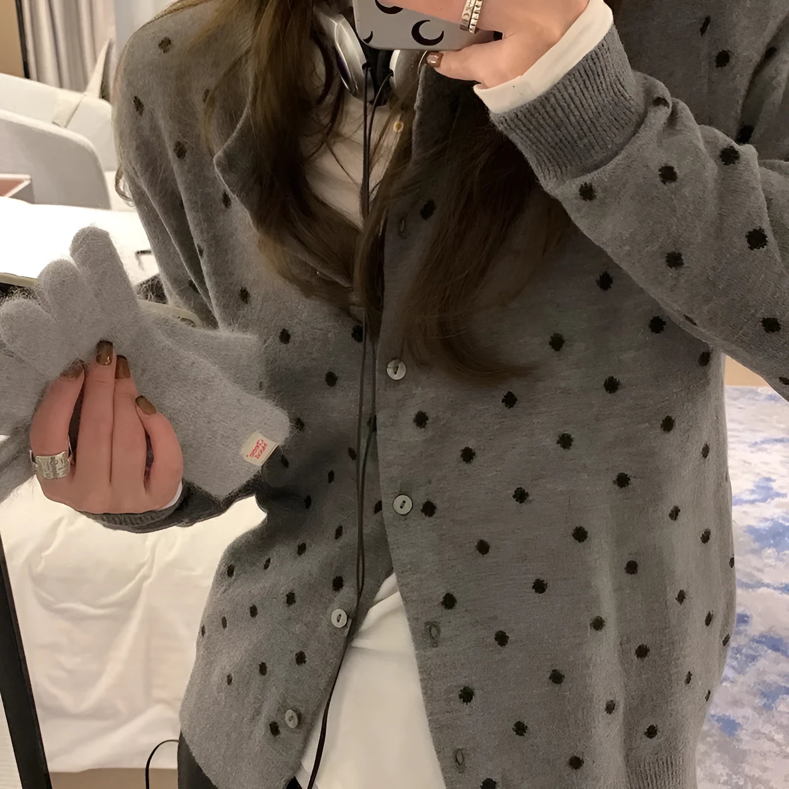 Grey dot patterned women's knitted cardigan with crochet flower details on a hanger.