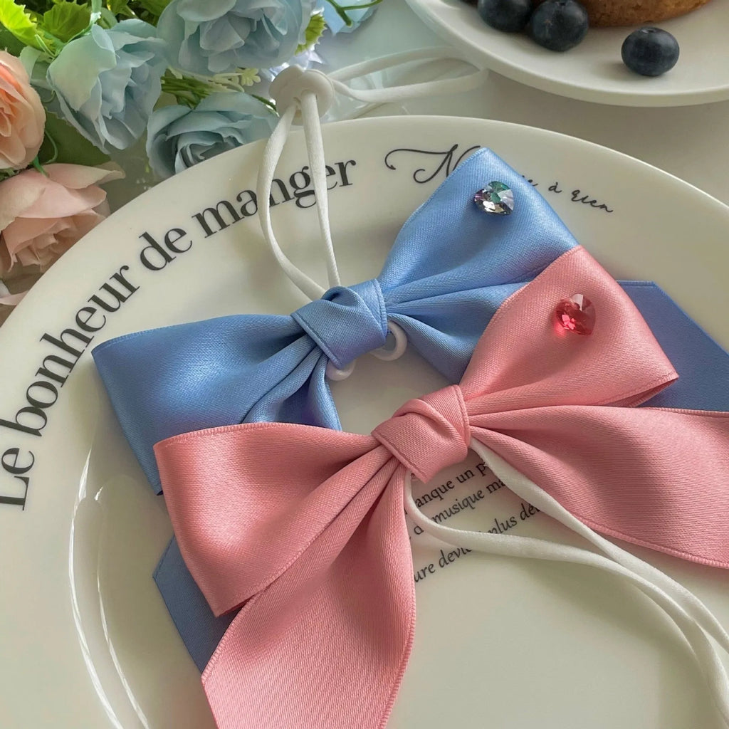 Adjustable blue dog hair band with a large pink princess bow on a white background