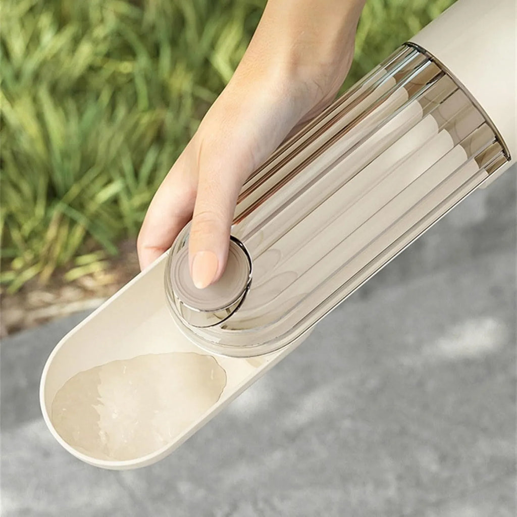 Beige collapsible dog water bottle with food container at base, showing press dispenser and tray.