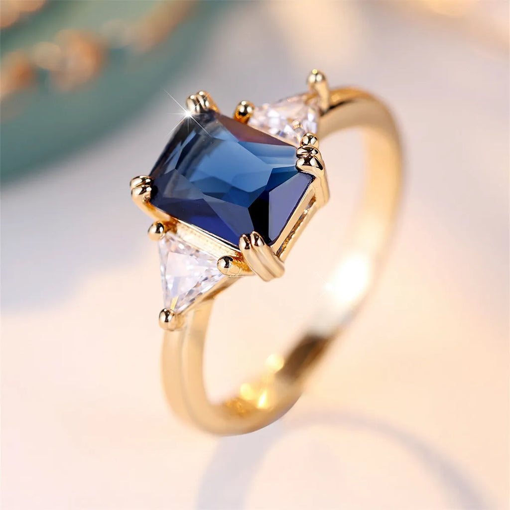 Women's rectangular copper ring in gold sapphire blue on a neutral background, showing its geometric band shape.