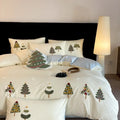 Pure cotton Christmas tree towel embroidery bedding four-piece set in cream blue on a bed.