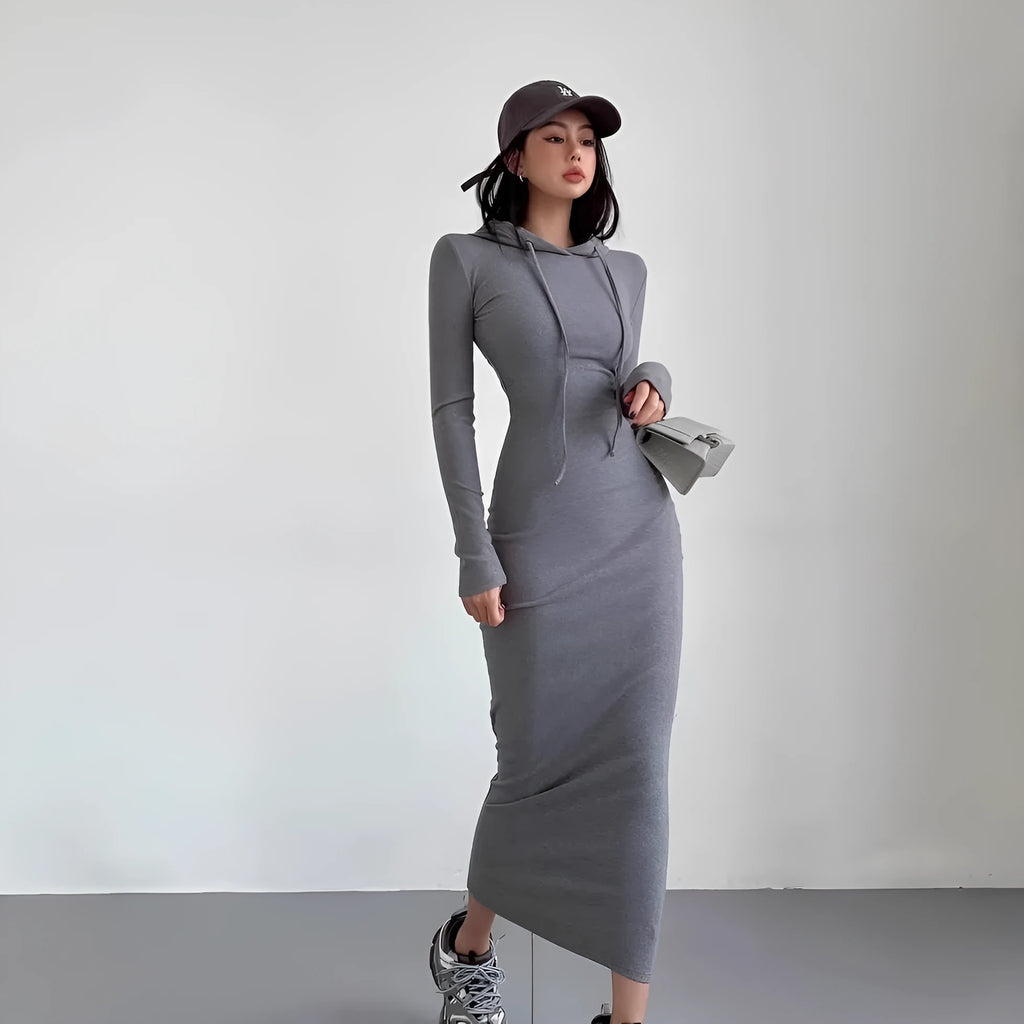 A woman wearing a light grey, long-sleeve polyester sheath dress with an over-the-knee length and high waist.