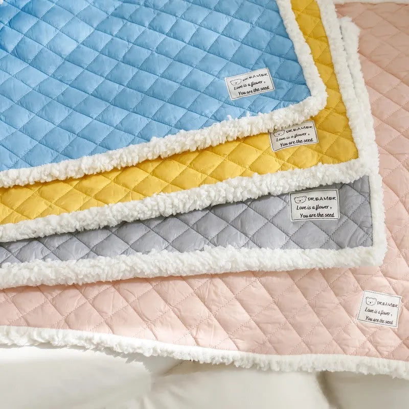 Quilted blue terry cloth pet blanket for cats shown on a pet bed.