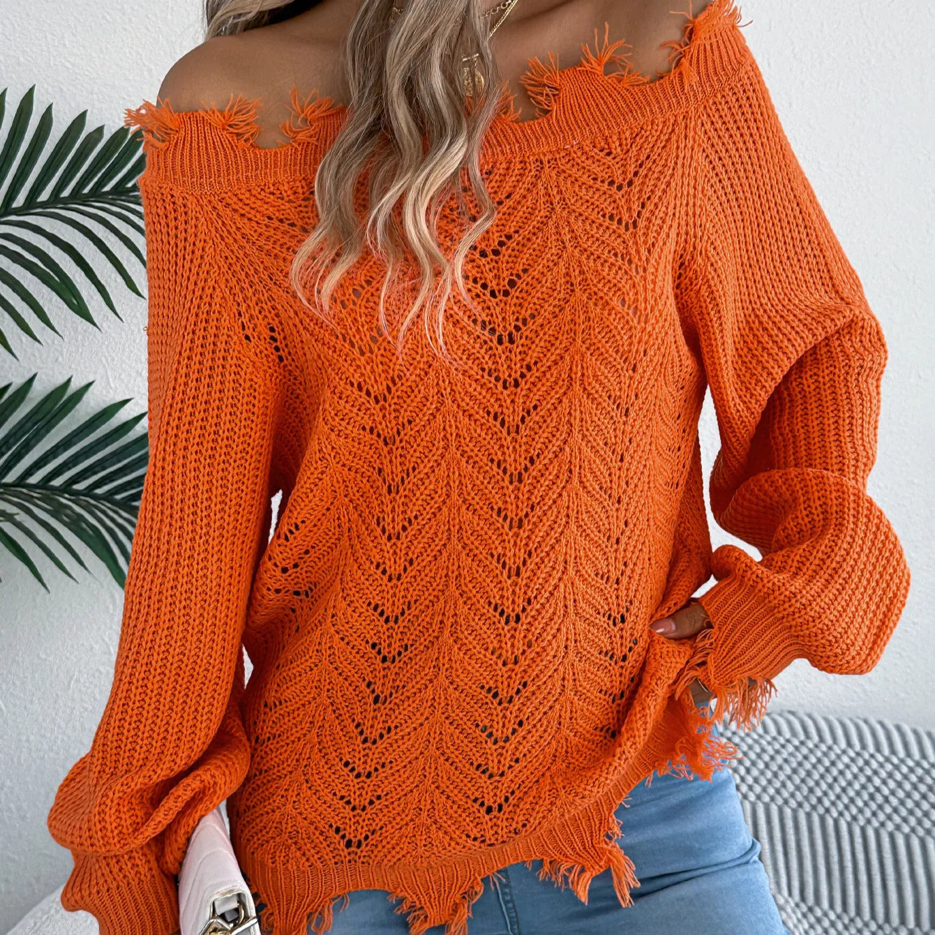White hollow-out long-sleeved pullover sweater with an off-the-shoulder cut and regular sleeves on a hanger.