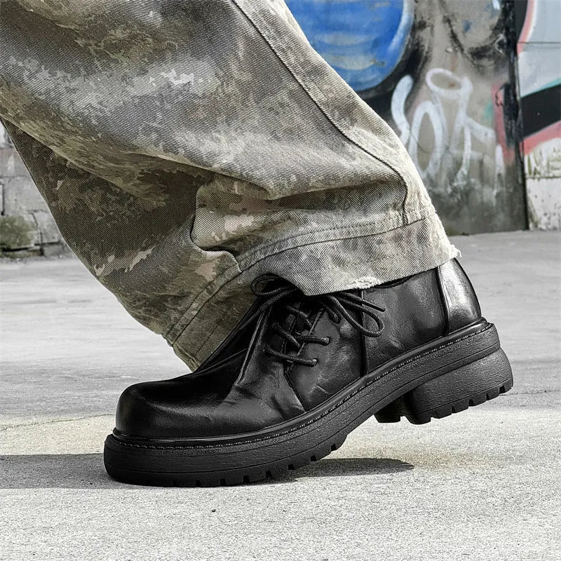 Black leather-style platform shoes with a round toe and low-top design on a white background.