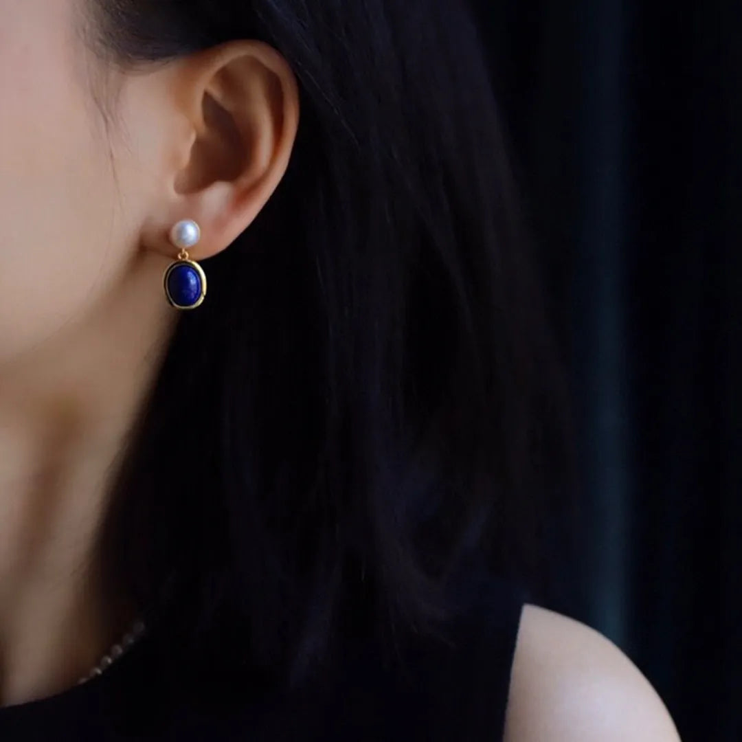 A pair of simple sterling silver stud earrings with a blue lapis lazuli pearl drop.