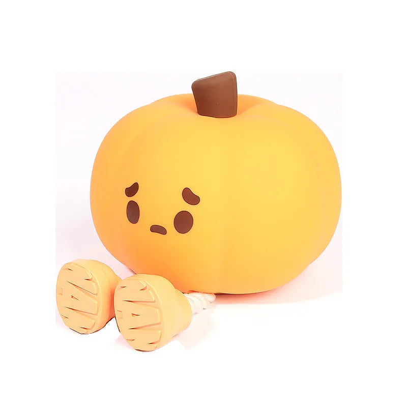 Soft orange silicone pumpkin-shaped night light with a warm glow on a bedside table.