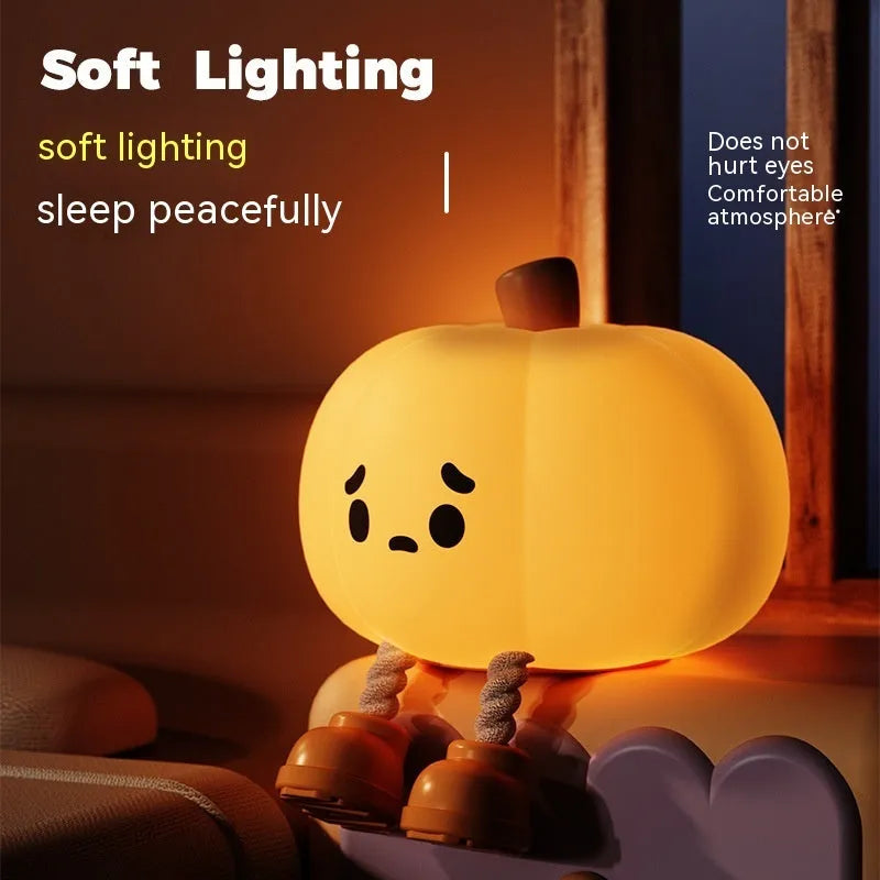 Soft orange silicone pumpkin-shaped night light with a warm glow on a bedside table.