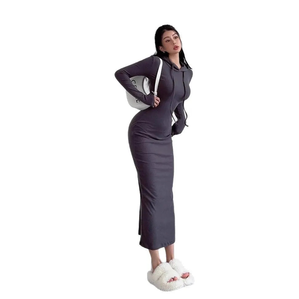 A woman wearing a light grey, long-sleeve polyester sheath dress with an over-the-knee length and high waist.