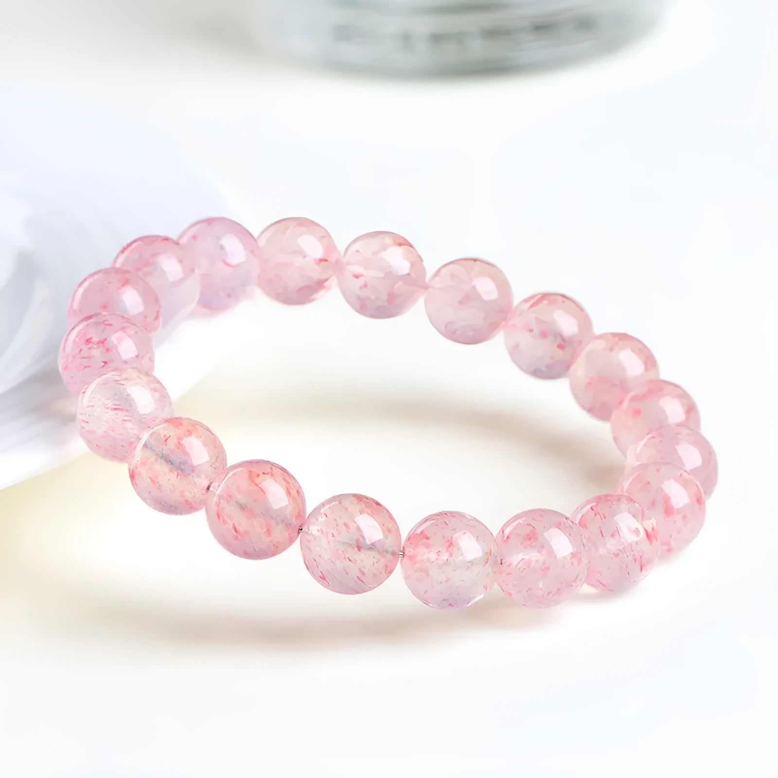 Natural white water strawberry quartz geometric ball bracelet with 10-10.8mm beads on a wrist.