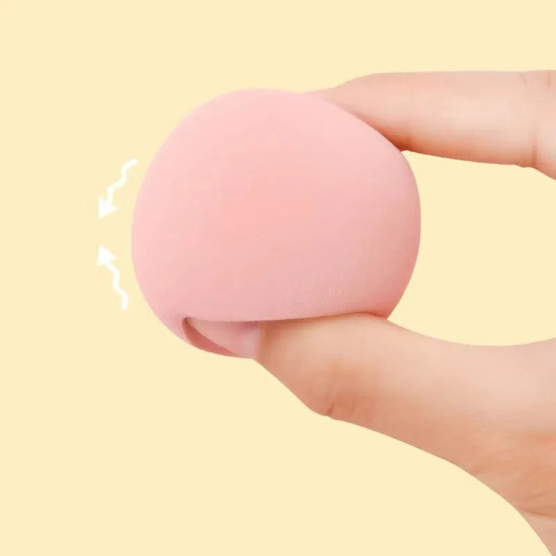 Set of seven differently shaped makeup sponges in various colours on pink background