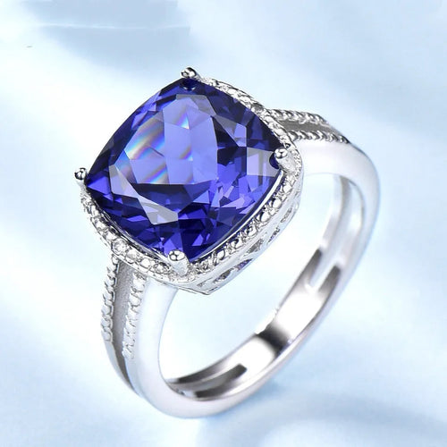 Blue Tanzanite stone set in a sterling silver women's ring on a plain background.