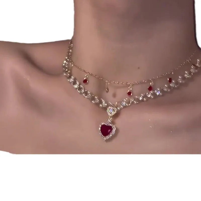 Gold tone double chain necklace with a central red love pearl pendant on an adjustable chain.