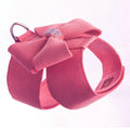 A pink microfiber dog chest strap with a large decorative bowknot and metal buckle.