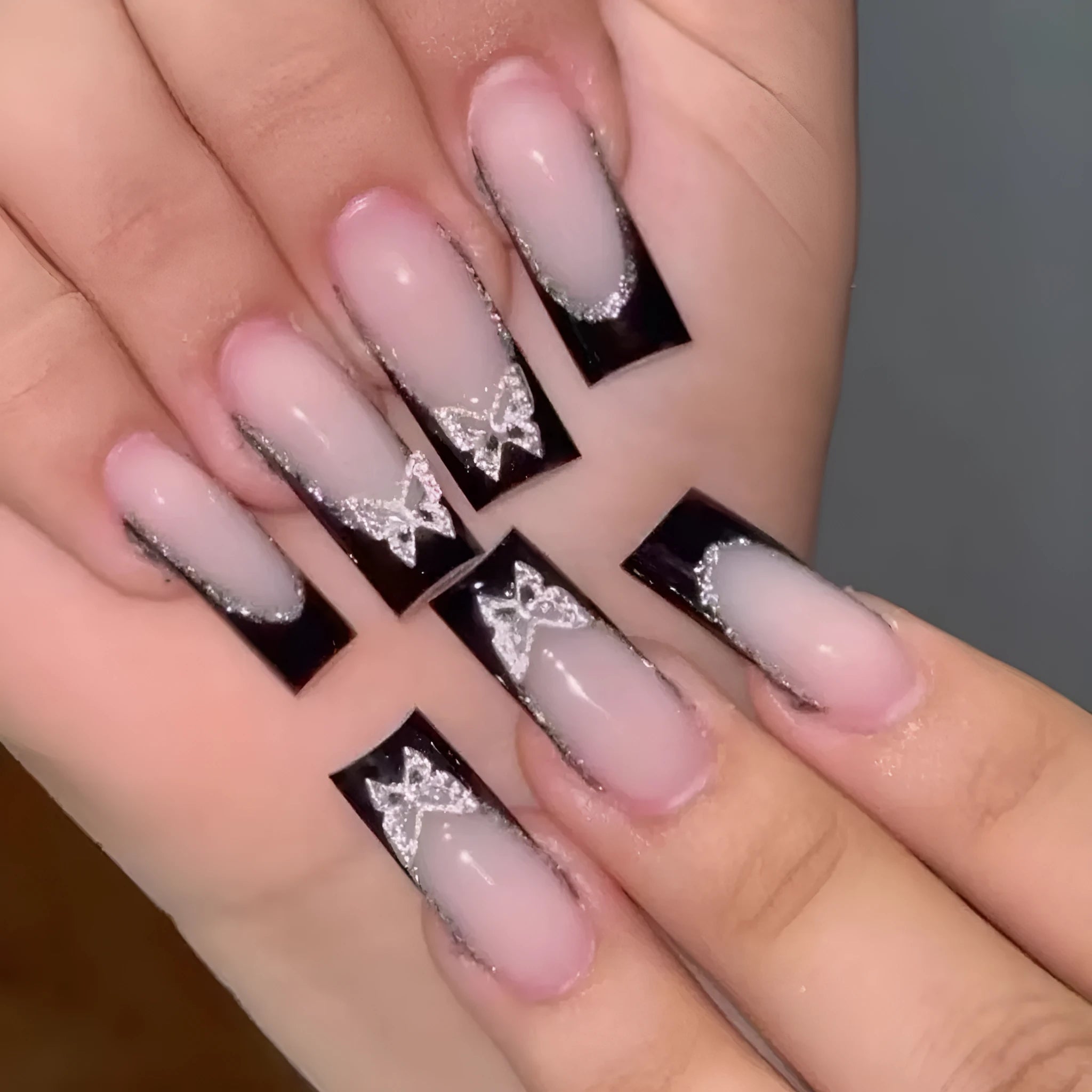 Black French style false nails with glittering butterfly design, medium length, from the BW50 Wear Armor set.