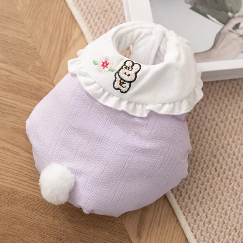 Bunny embroidered pet coat with ruffled white collar and fluffy pom-pom tail in lavender colour on a small dog