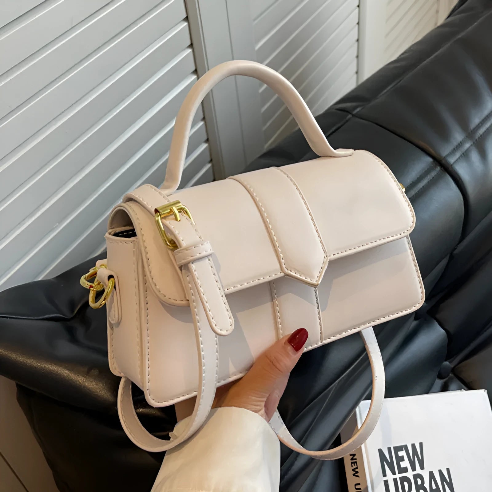 Beige women's square messenger bag with a top handle and shoulder strap, showing an outer pocket.