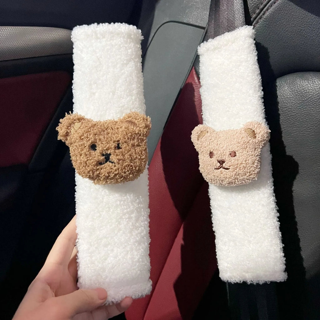 Plush cartoon bear car seat belt shoulder cover in khaki colour, shown next to a car seat.