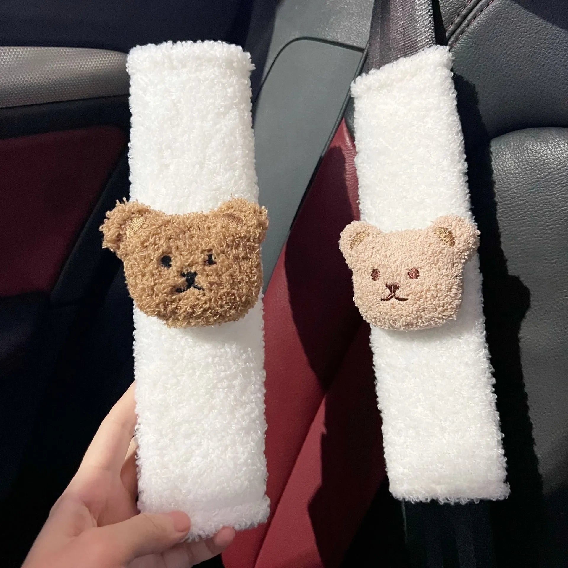 Plush cartoon bear car seat belt shoulder cover in khaki colour, shown next to a car seat.