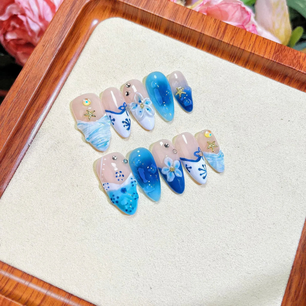 Set of 24 blue hand-painted fake nails with carved summer ice transparent design, showing sizes XS, S, M, L.