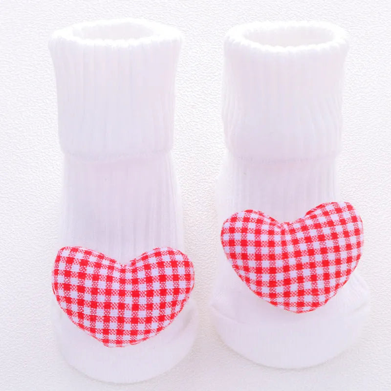 Cotton baby floor socks in a pink bow pattern, shown on an infant's feet.