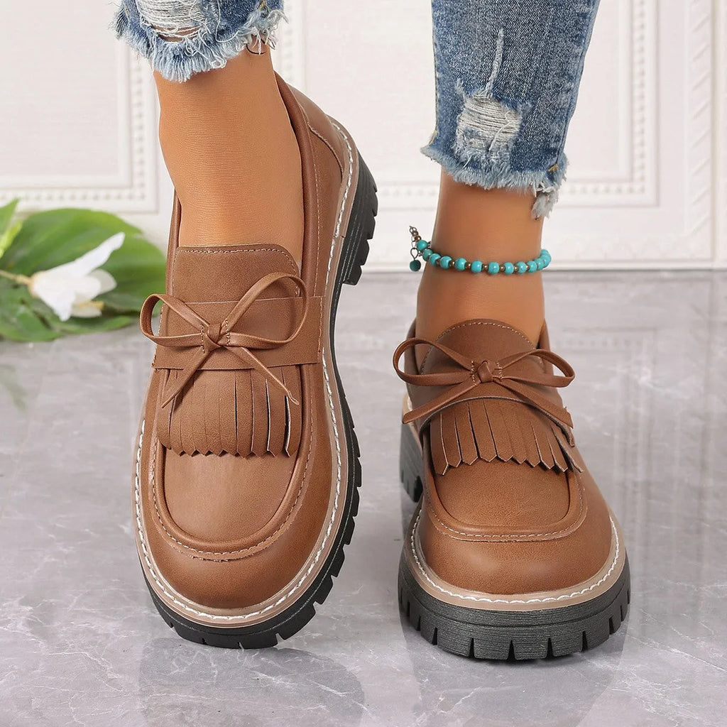 Black plus size women's loafers with a tassel and bowknot on a round toe, low top design.