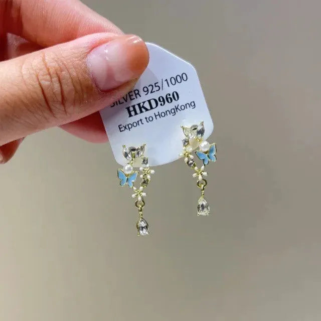 Close-up of a women's geometric alloy ear clip with rhinestones, a star charm, and a tassel on a white background.