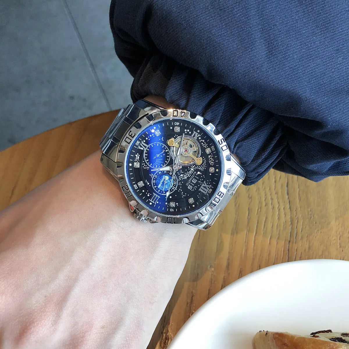 Silver men's automatic watch with black steel belt and luminous starry dial.