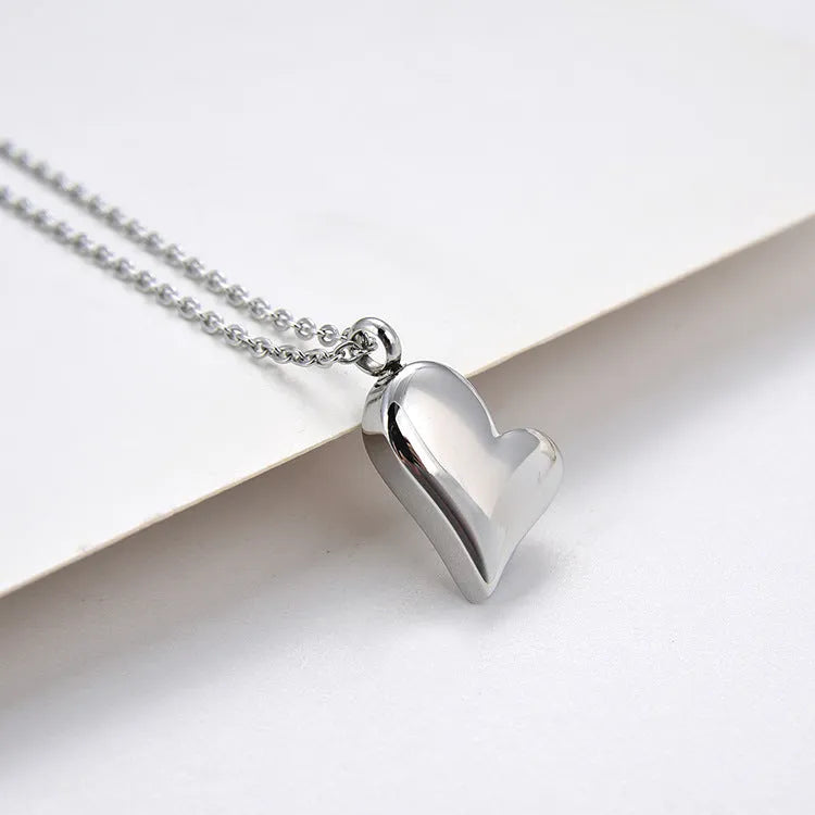 Silver curved peach heart pendant on a stainless steel necklace chain with an extension.