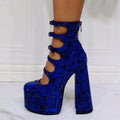 Women's black patent leather platform ankle boots with a serpentine buckle strap and thick heel.