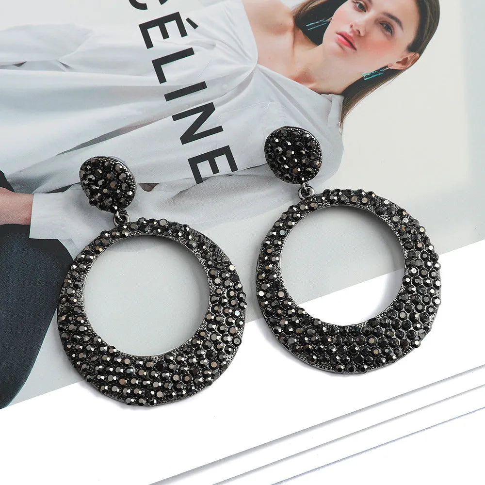 Large round cartoon-style alloy drop earrings with colourful diamond pendant on a white background.
