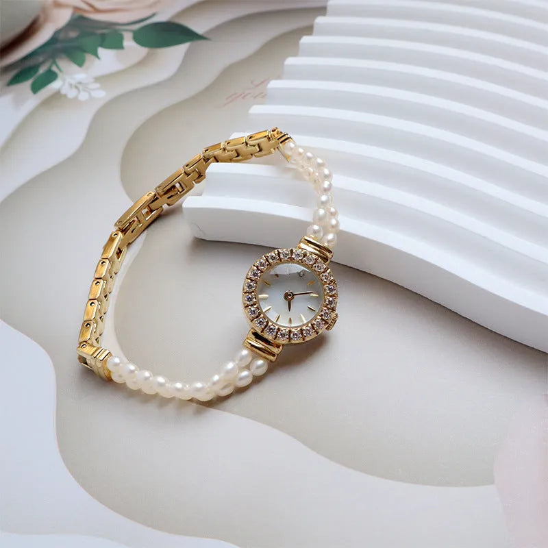 Women's light gold bracelet watch with freshwater pearls and a round 18mm dial.