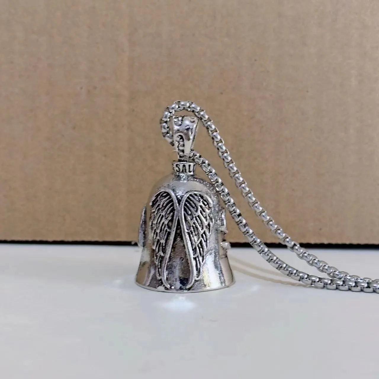 Vintage white angel feather alloy keychain and necklace on a dark background.