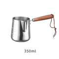 Stainless steel measuring milk cup with wooden handle showing scale markings.